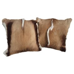 two brown and white cow hide pillows sitting side by side on top of each other