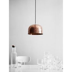 a white table topped with lots of wine glasses and a copper light hanging over it