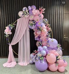 a balloon arch with balloons and flowers on it