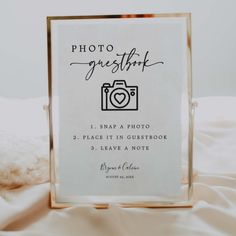 a photo frame sitting on top of a bed next to a white blanket and pillows