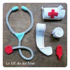 crocheted medical supplies laid out on a wooden table, including a stethoscope