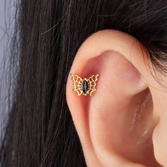 a close up of a person's ear with a butterfly shaped piercing