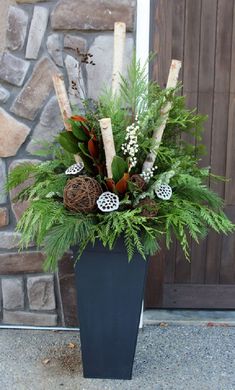 a vase filled with greenery and pine cones