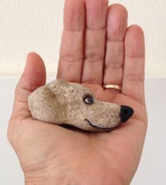 a hand holding a rock with a dog's face on it