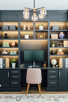 a desk with a monitor and some lights on it in front of a bookcase