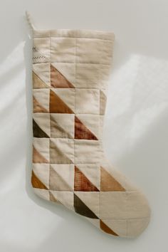 a quilted stocking hanging from the side on a white wall with shadows coming through it