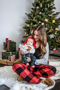 a woman holding a baby in front of a christmas tree