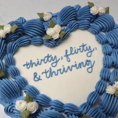 a heart shaped cake with the words thirty, fifty and thriving written in blue icing