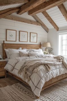 a large bed in a bedroom with white walls and wooden beams on the ceiling, along with two windows