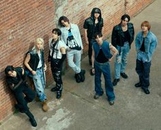 a group of young men standing next to a brick wall