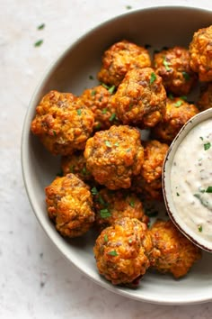 a white bowl filled with meatballs and dip