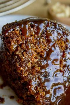 a close up of a piece of cake on a plate with chocolate sauce and nuts