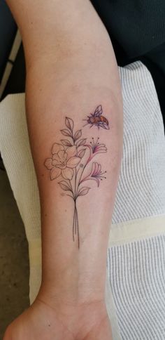 a woman's arm with flowers on it and a butterfly flying over the flower