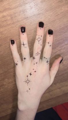 a person's hand with black nail polish and cross tattoos on their left thumb