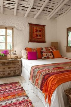 a bed sitting under a window next to a wooden dresser and rug on top of a white floor