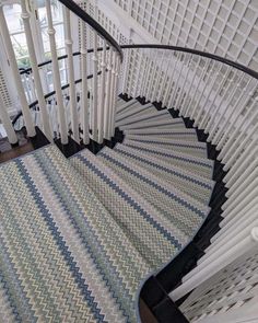 a spiral staircase in a home with white railings and blue carpeted stair mats