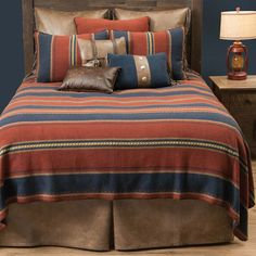 a bed with brown and blue comforters in a bedroom next to a night stand