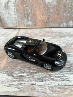 a black toy car sitting on top of a wooden table