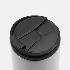 a white coffee cup with black lid on a white surface, viewed from the side