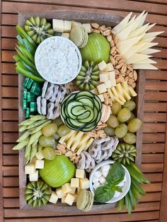 an assortment of cheeses, fruits and vegetables arranged on a board