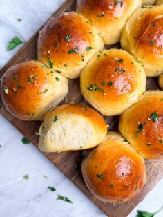 freshly baked bread rolls on a cutting board with parsley sprinkled on top