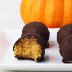 chocolate covered pumpkin truffles on a white plate with a pumpkin in the background