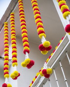 red, yellow and white pom - pom garlands hanging from the ceiling