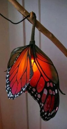 a light that is hanging from a branch with a butterfly on it's wings