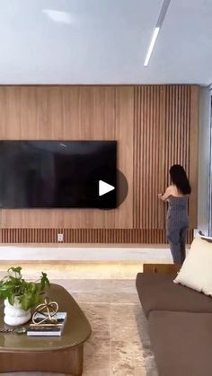 a woman standing in front of a flat screen tv next to a couch and coffee table