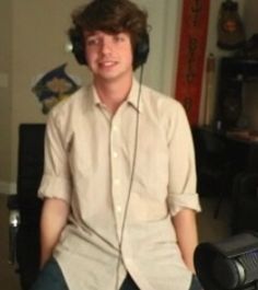 a young man wearing headphones sitting in front of a computer monitor and recording equipment