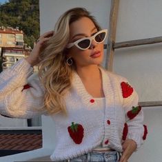 a woman wearing sunglasses and a sweater with strawberries on it