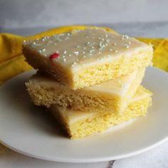 three pieces of cake sitting on top of a white plate next to a yellow napkin