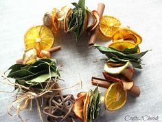 orange slices, cinnamon sticks and herbs arranged in a circle on a white table cloth