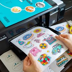 someone is printing stickers on a large sheet of paper in front of a printer