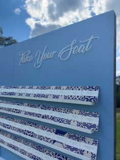 a sign that says take your seat with blue and white designs on the outside wall