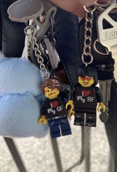 someone holding two lego keychains in their hands