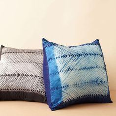 two blue and white pillows sitting next to each other