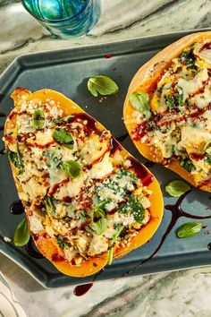 two stuffed butternuts with cheese and spinach are on a serving platter