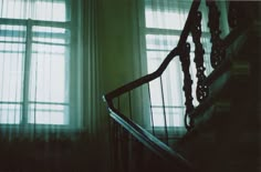 the stairs are next to two windows with sheer curtains