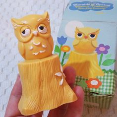 a yellow owl figurine sitting on top of a tree stump next to a box