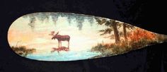 an animal painted on the side of a surfboard with trees and water in it