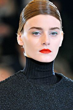 a model with red lipstick on the runway