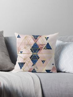 a pink and blue throw pillow sitting on top of a gray couch next to pillows