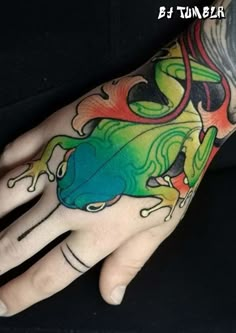 a person's hand with tattoos on it and a frog painted on the palm