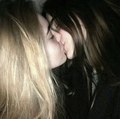 two women kissing each other in the dark