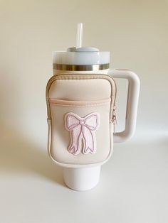 a white cup with a pink bow on the side and a straw in it's holder