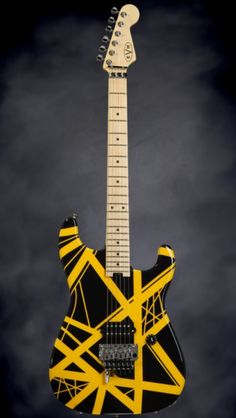 an electric guitar with yellow and black strips on it's body, against a dark background