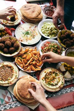 people are serving themselves food from plates on a table with many different types of foods