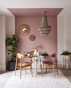 a dining room with pink walls and white rug on the floor, chandelier hanging from the ceiling