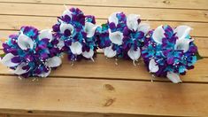 purple and white flowers are arranged on a wooden table with beaded trimmings